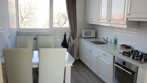 A modern kitchen with white cabinets, a microwave, a sink, and a Bosch oven. - Studio-Wohnung 'Studio Zeezicht' by Interhome (Vlissingen)