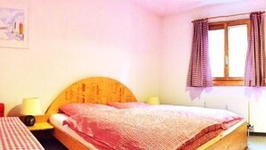 Un dormitorio con una cama de madera, una mesita de noche, una lámpara y una ventana con cortinas.