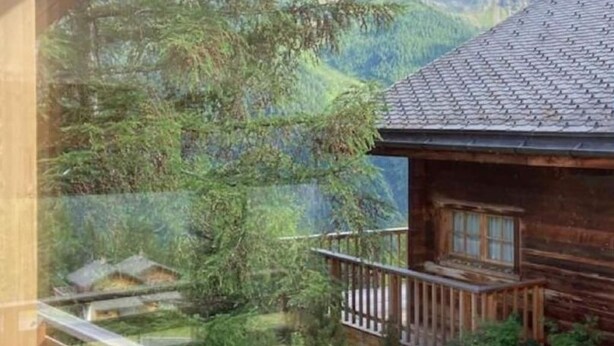 A wooden cabin with a balcony overlooking a mountainous landscape.
