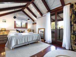 Un dormitorio con una cama grande, una ventana, un espejo y vistas al exterior.
