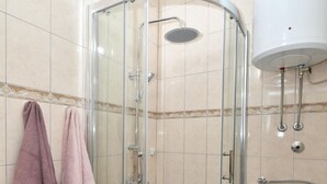 Une cabine de douche avec une porte en verre, des toilettes et un lavabo.