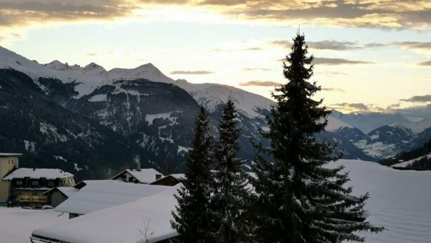 A snowy mountain landscape with a few buildings and trees in the foreground. - CasaMarmarolla by Interhome (Breil/Brigels)