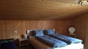 A wooden-paneled room with a single bed, a nightstand, and a chair. - CasaMarmarolla by Interhome (Breil/Brigels)