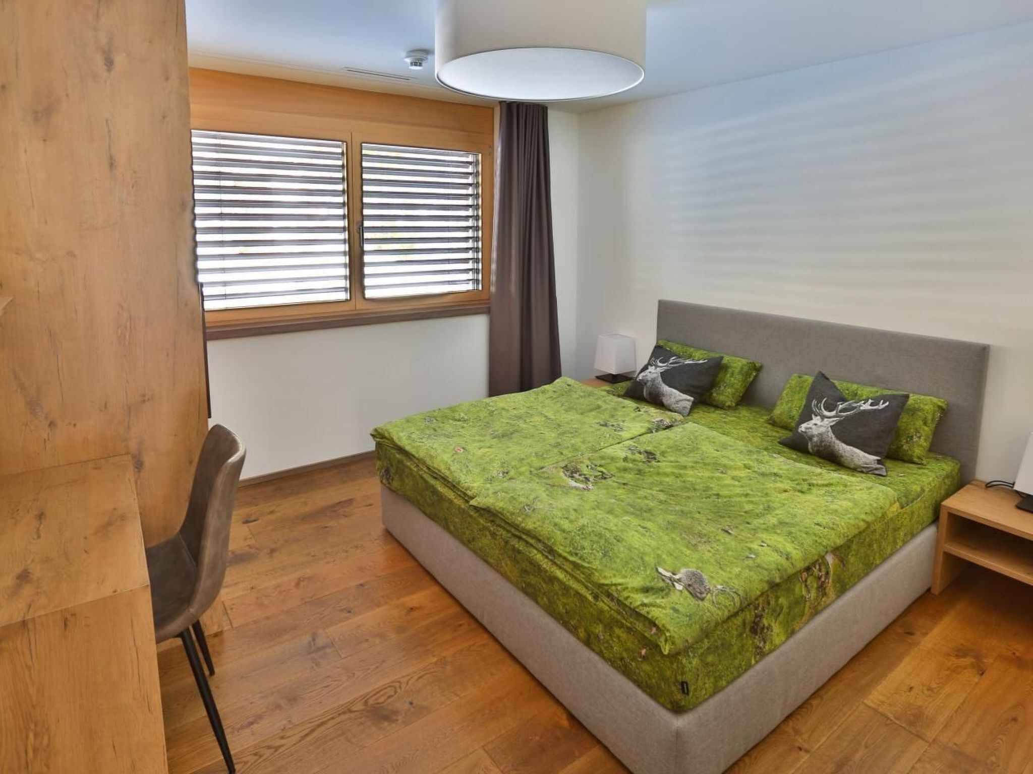 Un dormitorio con una cama grande, un escritorio y una ventana con persianas.