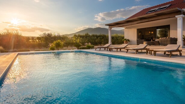 Una piscina con sillones de descanso, un porche cubierto y vistas a montañas.