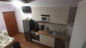 Kompakti keittiö, jossa on mikroaaltouuni, liesi, pesuallas ja pieni työtaso.