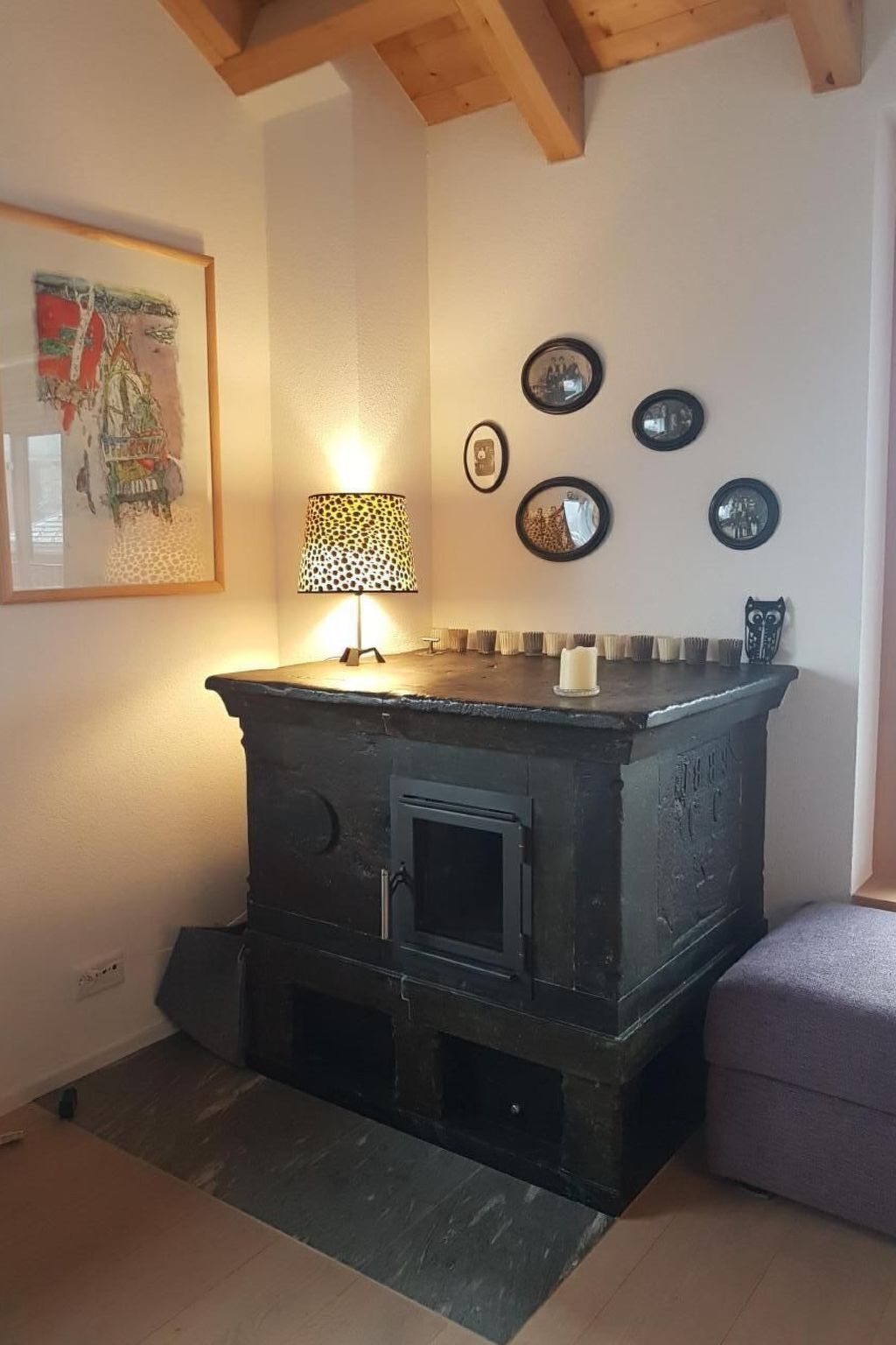 Una habitación con una estufa negra, un cuadro enmarcado y varios espejos redondos en la pared.