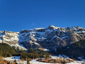 Een bergachtig landschap met besneeuwde toppen en een helderblauwe lucht.