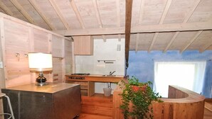 Un interior de madera con una zona de cocina, una barra y una planta colgante.
