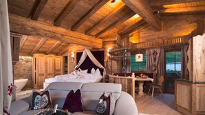 Ein gemütliches Holzhaus mit einem großen Bett, einer Essecke und einem Kamin.