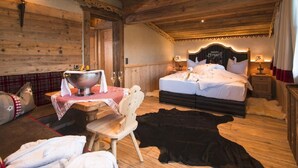 Ein Zimmer mit Holzboden, einem Bett, einem Tisch mit einer Schüssel und einem Stuhl.