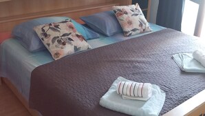 Ein Bett mit einer braunen Steppdecke, floralen Kissen und einem zusammengerollten Handtuch.