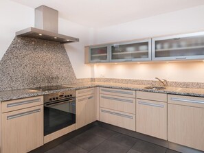 Eine moderne Küche mit Granit Arbeitsplatten, Edelstahlgeräten und hellen Holzschränken.