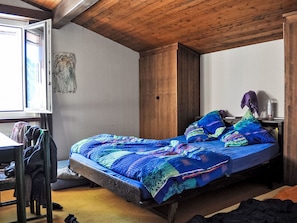 Una habitación con cama, techo de madera, ventana y un cuadro en la pared.
