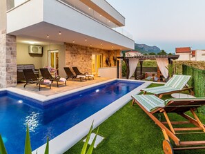 A modern outdoor pool area with lounge chairs and a stone wall. - Villa Olea- Pool, Grill, Nähe Flughafen Split by Interhome (Kaštel Sućurac)