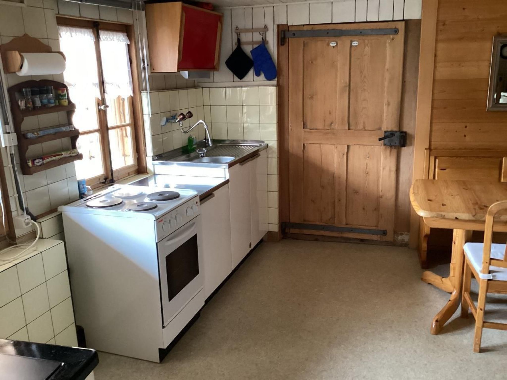 Une petite cuisine équipée d’une cuisinière, d’un évier et d’une porte en bois.