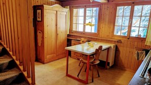 Un interior de madera con una mesa de comedor, sillas, una zona de cocina y una escalera.
