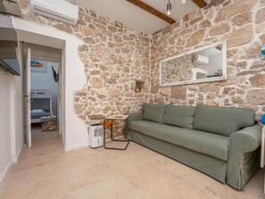 Ein Zimmer mit einer Steinsturz, einem grünen Sofa, einem Spiegel und einer weißen Klimaanlage.