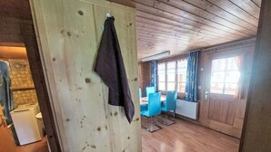 A wooden-paneled room with a dining area featuring blue chairs and a table. - Ferienwohnung mit Bergpanorama by Interhome (Zweisimmen)