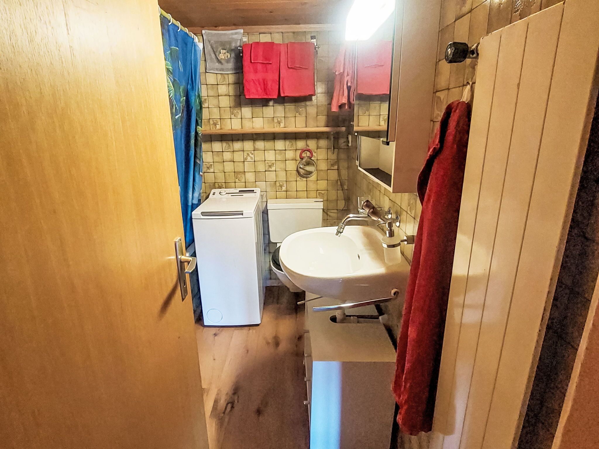 Une petite salle de bain avec un lavabo blanc, des toilettes et un lave-linge.