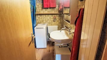 Une petite salle de bain avec un lavabo blanc, des toilettes et un lave-linge.