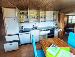 Een koelkast, een oven, een vaatwasser, kookgerei, borden en bestek