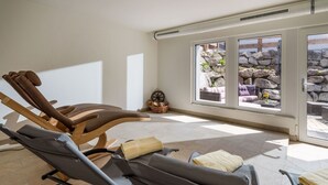 A sunroom with a view of a stone wall and plants, equipped with reclining chairs and a wooden ceiling. - Appartement "Hochgefühl" by Interhome (Leutasch)