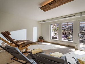 A sunroom with a view of a stone wall and plants, equipped with reclining chairs and a wooden ceiling. - Appartement "Hochgefühl" by Interhome (Leutasch)
