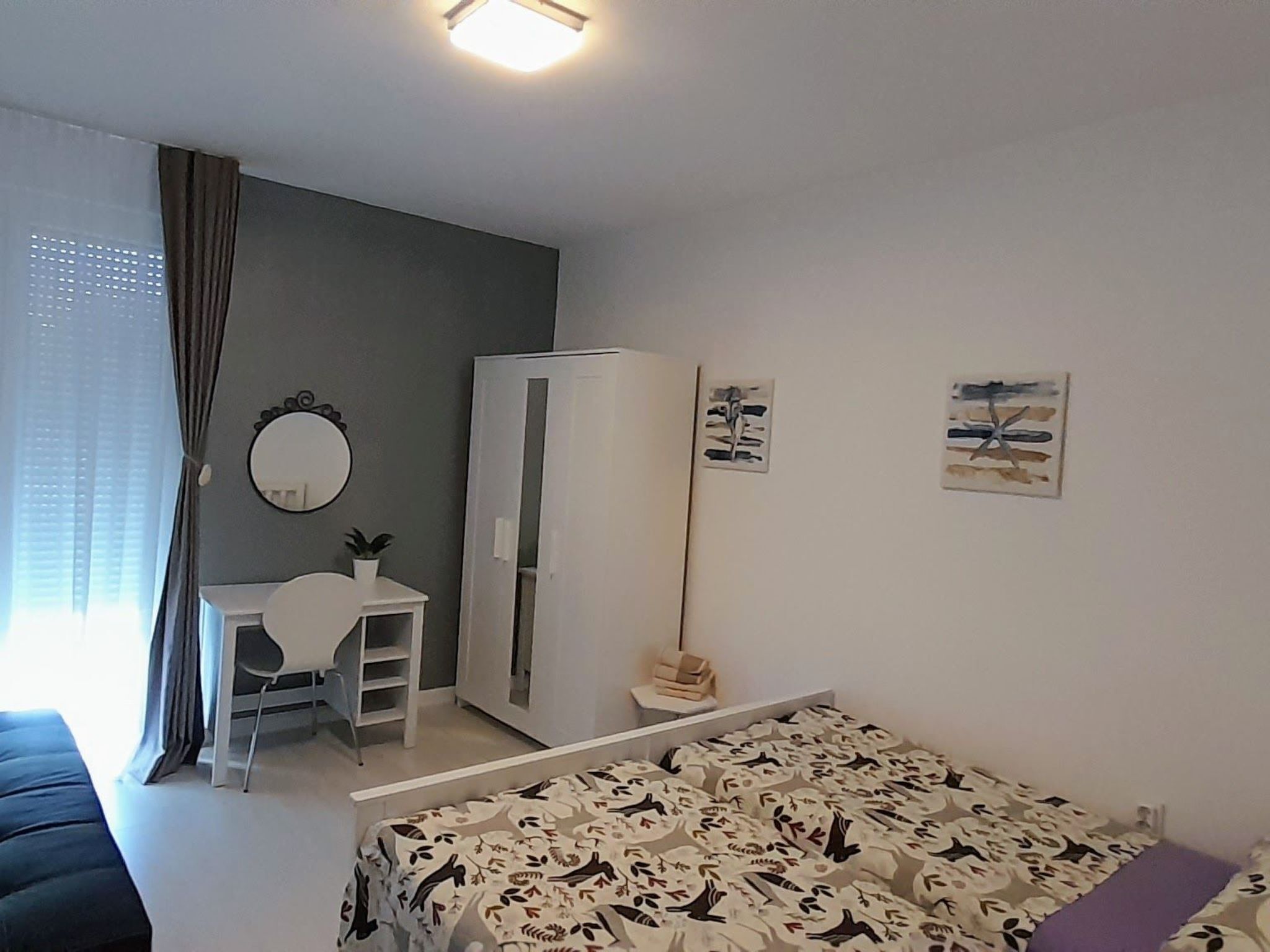 Una camera da letto con un letto, una scrivania, un armadio e uno specchio.
