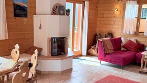A cozy cabin interior with a wooden interior, a fireplace, a pink sofa, and a dining area with wooden chairs. - Chalet Poiema by Interhome (Bellwald)