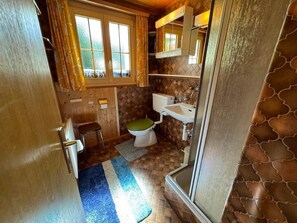 Un baño pequeño y funcional con inodoro, lavamanos y un taburete.