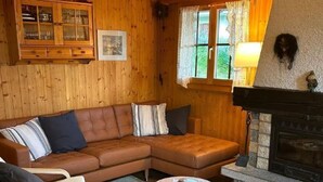 A cozy cabin interior with a wooden ceiling, a fireplace, a leather sofa, and two armchairs. - Chalet Glücksfall by Interhome (Bellwald)
