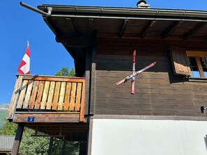 Un edificio de madera con balcón, una bandera y esquíes colocados en la pared.