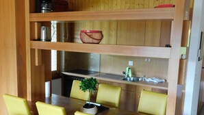 A compact kitchen with a dining area, featuring a wooden table and chairs, a sink, and a stove. - Residence Edelweiss A131 by Interhome (Bellwald)