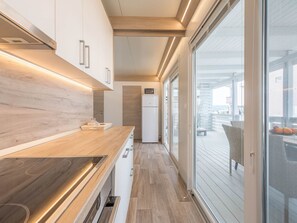 Una cocina moderna con encimeras de madera, horno empotrado y vista a la terraza exterior.