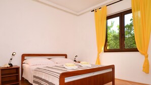 Un lit bien fait, recouvert d’une couvre-lit à rayures, une lampe de chevet et une table de chevet avec une lampe.