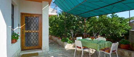 A patio with a table and chairs, a covered area, and potted plants.