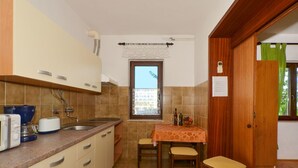 Une cuisine compacte avec un coin repas, comprenant une fenêtre, un évier et une table dressée pour deux personnes.