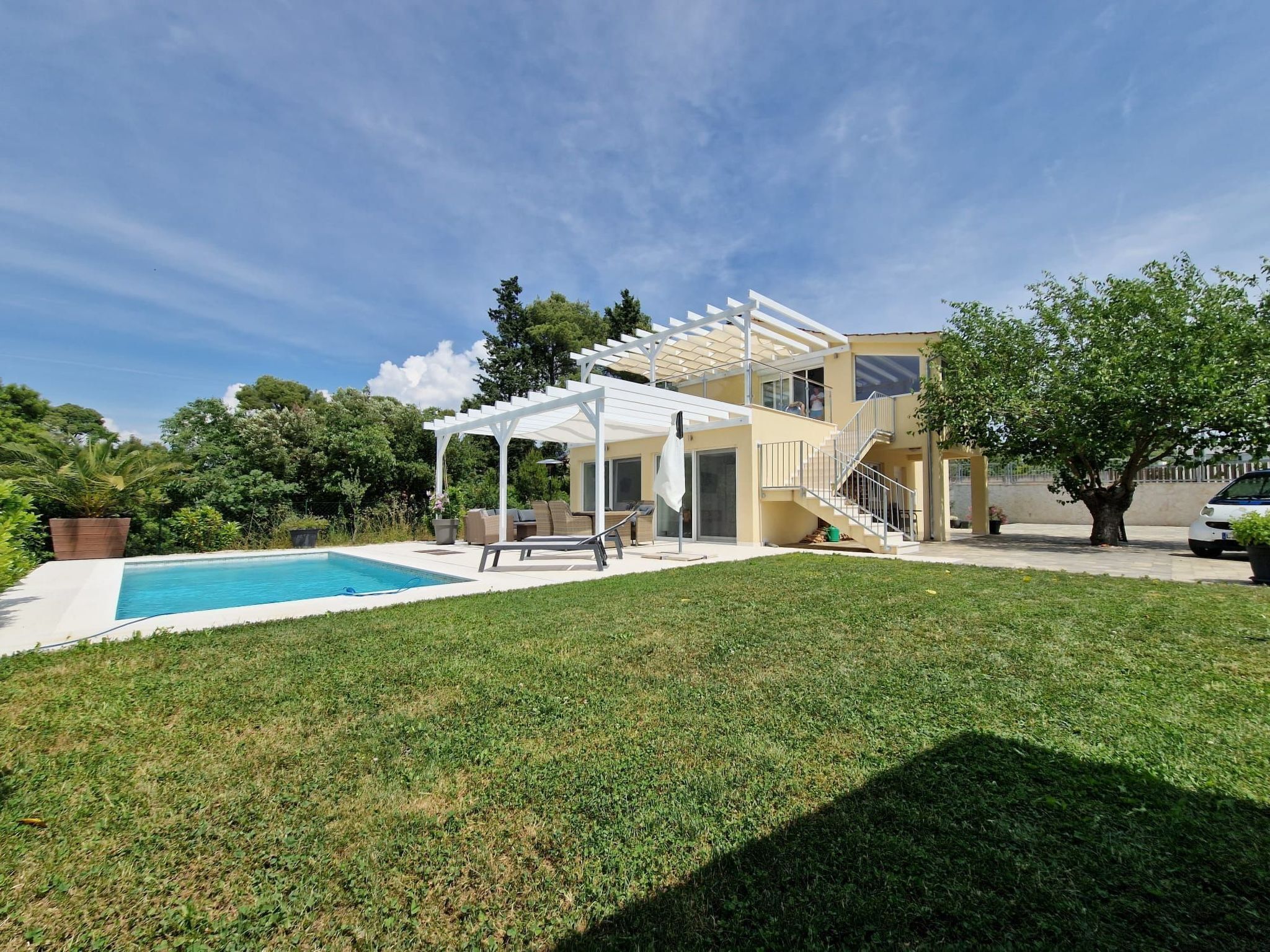 A two-story house with a covered patio, a swimming pool, and a well-maintained lawn.