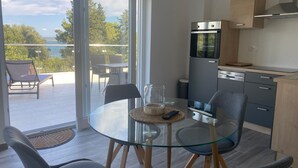 Una cocina moderna con horno empotrado y comedor con mesa y sillas de vidrio.