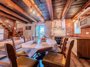Un coin repas au style rustique, avec des poutres apparentes, un mur en briques et une vue sur l’extérieur.