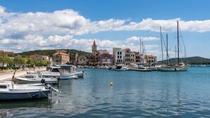 A marina with boats docked, a prominent church with a bell tower, and a hilly backdrop. - Wohnung in Pirovac mit Terrasse, Garten und Grill by Interhome (Pirovac)