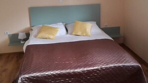 Una camera d'albergo con un letto, due cuscini, un comodino e una lampada.