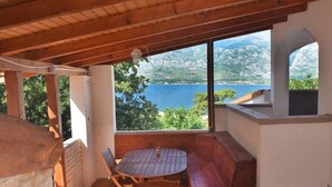 Un'area salotto all'aperto riparata, con tavolo e sedie, affacciata su un lago e montagne panoramici.