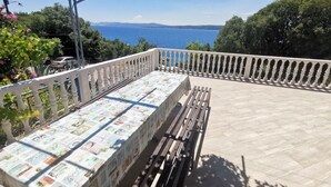 A balcony with a table covered in a tablecloth displaying various images, overlooking a body of water and distant mountains. - Wunderschöne Wohnung in Dramalj 70m vom Meer entfernt by Interhome (Crikvenica/Dramalj)