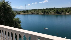 A balcony with a view of a calm lake, surrounded by greenery and a distant power line tower. - Ferienwohnung by Interhome (Novigrad (Zadar))