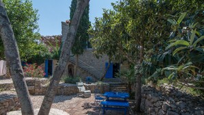 Ein Innenhof mit Steinmauern, einer Treppe sowie einem blauen Tisch und Stühlen.