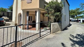 Ein zweistöckiges Gebäude mit Balkon, überdachter Terrasse und geschlossenem Eingangsbereich.