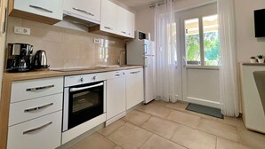 Eine moderne Küche mit weißen Schränken, einem Einbauofen, einer Kaffeemaschine und einem Kühlschrank.