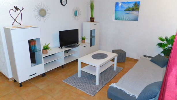 A modern living room with a flat-screen TV, white furniture, a small coffee table, and a sofa. - Apartman Slavica by Interhome (Karin)